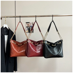 Close-up of quilted tote bags in brown, burgundy and black colors with chain straps
