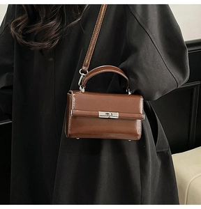 Detailed close-up of brown polished leather handbag with silver metallic rotating clasp
