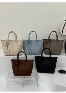 Cinq sacs cabas en cuir avec breloques éléphant présentés sur un décor minimaliste
