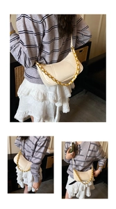 Detail of cream crescent bag featuring gold chain handle and fine stitching accents