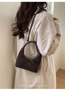 Detail view of a retro dark brown hobo bag with white contrast stitching and silver zipper