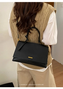 Detail of minimalist black matte leather tote bag with gold metal logo on model back