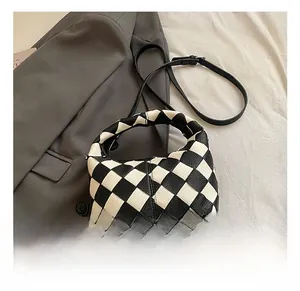 Détail du sac à damier tissé avec bandoulière noire et texture en cuir grainé