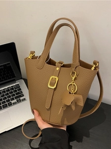 Brown bucket handbag with litchi texture featuring a gold buckle and cute elephant charm