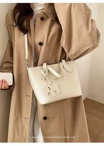 Gros plan sur le sac fourre-tout crème avec texture grainée et breloque éléphant