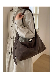 Detailed view of dark brown suede hobo bag with tassel accent styled on a model