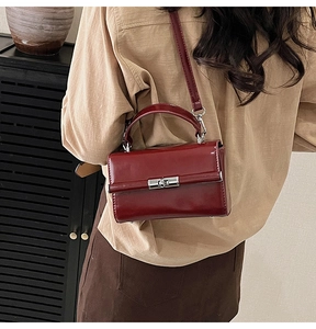 Deep red patent leather crossbody bag shown on a model in a minimal indoor setting