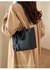Sac fourre-tout en cuir grainé noir avec charme éléphant porté à l'épaule par un mannequin