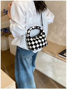 Détail d'un sac bandoulière à damier noir et blanc avec texture cuir PU et zip argenté