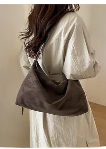 Brown oversized hobo bag on shoulder, showing slouchy matte texture and minimalist style