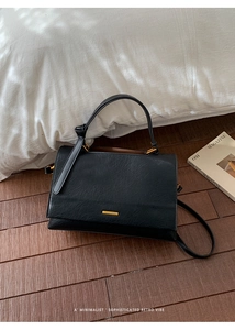 Macro view of black leather tote bag with subtle golden logo and textured finish