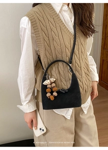 Detail of black semi-circular bag with polka dot bow and plush pom-pom charm