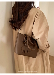 Détail d'un sac cabas en cuir grainé marron foncé avec un charm éléphant et bandoulière