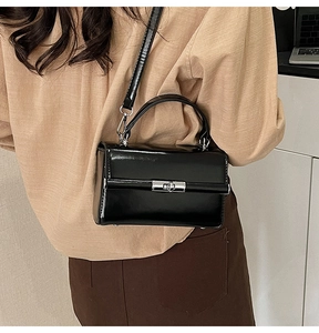 Glossy black square handbag with silver rotating clasp shown on model for size and fit