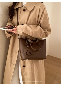 Détail d'un sac cabas en cuir grainé marron avec charme éléphant et clous de protection au fond