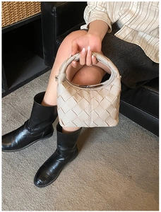 Vue détaillée du sac à main tressé blanc crème avec poignée incurvée et texture cuir