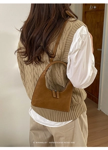 Close-up of brown leather hobo bag with contrast stitching and double zipper detail