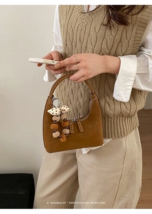 Detail of a brown vintage suede handbag with a decorative tassel and plush charm