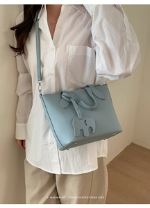 Détail du sac bleu clair en cuir texturé avec charm éléphant et clous de protection en métal