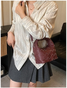 Détail du sac en cuir tressé bordeaux avec surpiqûres contrastées sur un mannequin