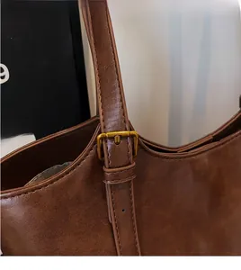 Détail de la bandoulière en cuir réglable et boucle dorée sur un sac cabas rétro