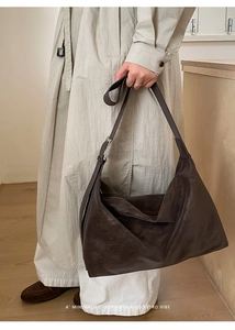 Detail of dark brown faux leather hobo bag with vintage texture and silver buckle