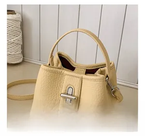 Detailed view of cream leather bucket bag showing lychee grain and silver turn-lock closure