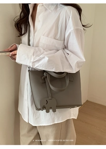 Détail du sac seau en cuir gris avec un pendentif éléphant minimaliste et pieds en métal