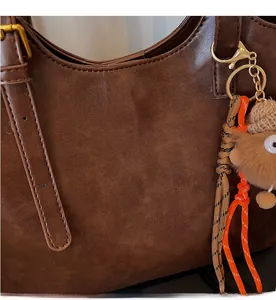 Vue détaillée du cabas marron foncé avec logo doré et charm peluche décoratif