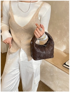 Détail de la texture en cuir tressé marron foncé sur un sac à main minimaliste