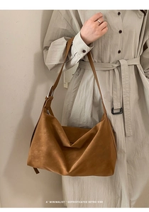 Detail of adjustable suede shoulder strap with silver buckle on brown hobo bag