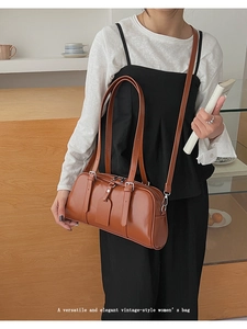 Detail showing high-shine caramel leather Boston bag with double zippers and long handles