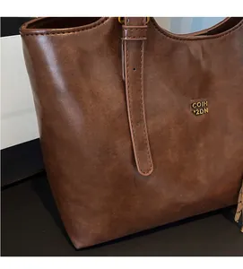 Gros plan sur un cabas en cuir marron foncé avec logo métallique doré COIH 2DN