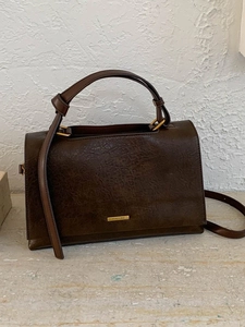 Minimalist dark brown leather handbag with top handle and adjustable shoulder strap