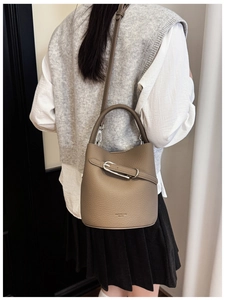Detail of taupe pebbled leather bucket bag with top handle and crossbody strap