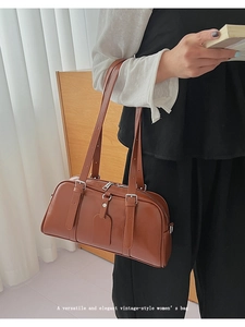 Detail of a brown retro boston handbag with long shoulder straps and silver buckles