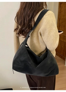 Close-up of black suede hobo bag showing minimalist design and wide shoulder strap