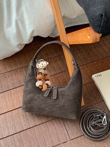 Deep grey hobo bag with contrast stitching and plush charm on a wooden background