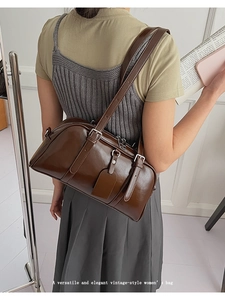 Brown vintage shoulder bag with dual zippers and buckle detail on a model
