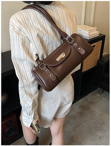 Detail of a dark brown leather barrel bag with a stylish metal buckle and retro vibes