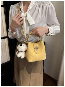 Detail of creamy yellow bucket bag with silver twist lock and plush puppy charm