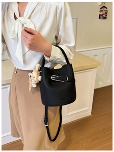 Close-up of black lychee grain leather bucket bag with silver hardware and bear charm