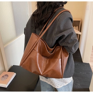 Dettaglio borsa tote color caramello con tasca laterale indossata a spalla in ufficio