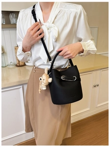 Chic black litchi grain bucket bag detail with a cute bear charm and silver hardware