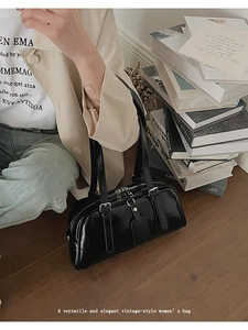 Detail of a vintage black glossy leather Boston bag styled with a beige blazer outfit