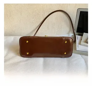 Detail shot of brown leather bag bottom with four gold protective metal feet