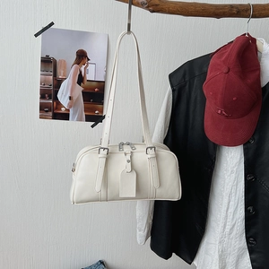 Detail view of a cream Boston bag with silver hardware hanging on a wooden branch