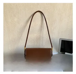 Detail shot of brown glossy leather baguette bag with a golden square metal buckle closure
