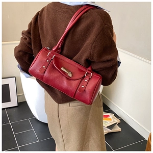 Model wearing a deep red vintage Boston bag with glossy finish and stylish shoulder strap