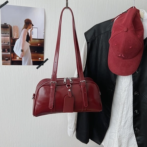 Close-up of deep red glossy faux leather Boston bag with silver buckles and dual thin straps